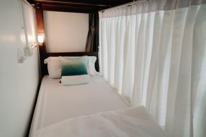 南府Mystay Hostel Nan的白色窗帘的房间的一张床位
