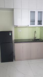 河内Era Apartment Xuân Thuỷ的厨房配有黑冰箱和白色橱柜。