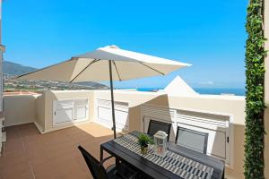 拉奥罗塔瓦Atico Mencey的庭院配有遮阳伞和桌椅