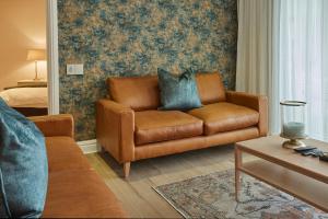 开普敦African Elite Waterfront的客厅配有棕色真皮沙发和床。