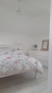 戈里Amberley的白色卧室配有带花卉棉被的床