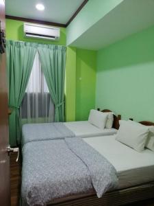 马六甲1511旅馆的配有两张床的客房,设有绿色的墙壁和窗户