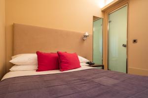 雅典海洛狄恩酒店的一间卧室配有一张带两个红色枕头的床