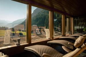 图克斯图克塞尔霍夫阿尔卑斯温泉酒店的一间带椅子的房间和一个享有山景的大窗户