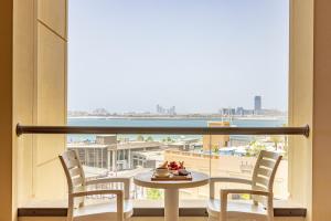 迪拜朱美拉海滩住宅区罗达安瓦吉套房酒店的客房设有桌椅和大窗户。