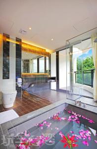 鱼池乡日月潭水岸休闲饭店(二馆)的浴室设有位于地板上的鲜花游泳池
