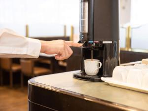 铃鹿市Hotel Castle Inn Suzuka的一个人把咖啡倒进咖啡机里