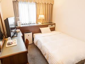 铃鹿市Hotel Castle Inn Suzuka的酒店客房配有一张床和一张书桌及一台电视