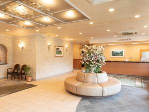 铃鹿市Hotel Castle Inn Suzuka Chuo的大堂设有等候室,中央插花