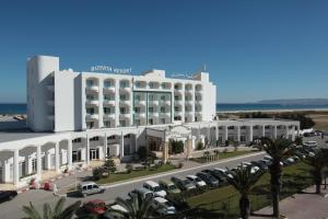 比塞大Bizerta Resort Congres & SPA的一座白色的大建筑,汽车停在停车场