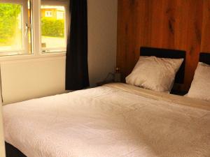 HaulerwijkDetached chalet in Friesland with fenced garden的卧室内的一张床铺,带窗户