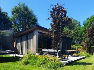 HaulerwijkDetached chalet in Friesland with fenced garden的花园中的小屋,配有桌椅