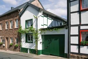 尼德根Gemütliches Fachwerkhaus im Herzen Nideggens的一座带绿门和砖砌建筑的白色房子