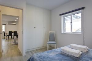 洛萨达Casa de Cristelos的一间卧室设有一张床、一个窗口和一把椅子