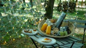 ParmilieuÔ Pays Des Bois - Hébergements insolites en pleine nature的一张野餐桌,上面放着一篮子的食物和橙汁
