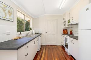 耶蓬Hughes Hideaway - 2BR Cottage on 1 Acre w Air Con, King Beds的厨房铺有木地板,配有白色橱柜。
