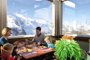 里蒙纽耶Belambra Clubs Les Menuires - Neige Et Ciel的家庭在山景餐厅餐桌上用餐