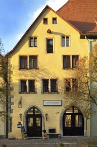 罗滕堡赫尼施洛斯臣酒店的黄色的建筑,前面有标志