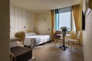 维亚雷焦伦敦酒店的酒店客房带一张床、一张桌子和椅子