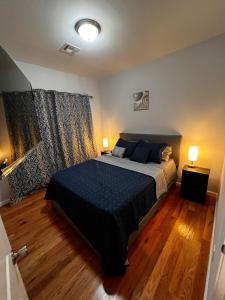纽瓦克SPRINGVIEW HOMES 12MINS FROM EWR & 3 MINS FROM UNIVERSITY HOSPITAL的一间卧室配有一张带蓝色床单的床和两盏灯。