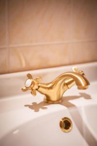 塞布尼茨ApartOne Land-Hotel的白色浴室水槽上的金色水龙头