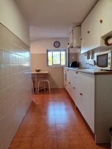 辛特拉Alojamento 3 vistas的厨房配有白色橱柜和桌子