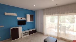塔拉戈纳Apartamentos Cala Azul La Móra的客厅配有电视和蓝色的墙壁