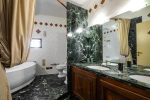 卡利亚里卡斯特伦旅馆的一间带两个盥洗盆、浴缸和卫生间的浴室
