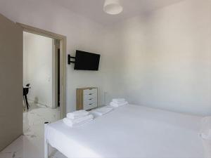 赫索尼索斯Hersonissos Modern One Bedroom Apartment Beachside的白色卧室设有一张床和墙上的电视