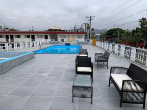 恩塞纳达港Hotel Presidente的一个带椅子的庭院和一个游泳池