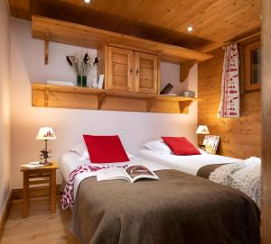 阿克1800Résidence Pierre & Vacances Premium Le Roselend的一间卧室配有两张带红色枕头的床和一本书
