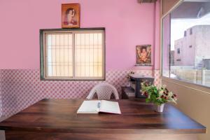 奥兰加巴德SPOT ON Shree Gajanan的粉红色的客房设有木桌和窗户。