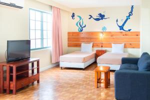 塔穆宁花园别墅酒店的客房设有两张床、一台电视和一张沙发。
