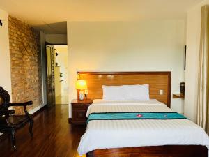 顺化武三维恩民宿的一间卧室配有一张大床和木制床头板