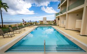 塔穆宁关岛假日Spa度假酒店的一座带海滩的建筑前的游泳池