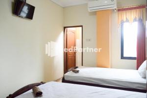 MojosongoPKPN Syariah Boyolali Mitra RedDoorz的客房设有两张床和一台墙上的电视。