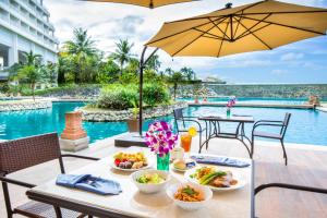 塔穆宁RIHGA Royal Laguna Guam Resort的一张桌子,旁边是一张桌子,上面有食物和遮阳伞