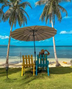 BuruangaTuburan Cove Beach Resort的海滩上两把椅子放在伞下