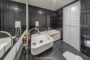 Ban Khlong PhruanThe Ring Border的黑色瓷砖浴室设有水槽和浴缸