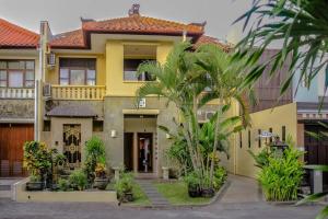 库塔5 Bedroom Holiday Villa - Kuta Regency B8的棕榈树前方的黄色房子