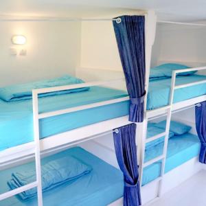 海神庙Swell Hotel, Pool Bar & Restaurant的配有蓝色窗帘的客房内的两张双层床