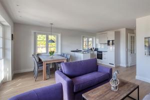 兰图姆Rantum Dorf - Ferienappartments im Reetdachhaus 3 & 4的客厅配有紫色沙发和桌子
