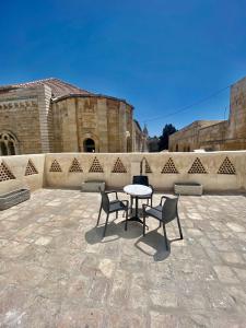 耶路撒冷Petrakis Inn的庭院设有桌子、两把椅子和墙壁