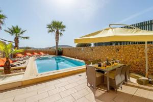 沙拉Tfiefa Holiday Home的一个带桌子和遮阳伞的庭院和一个游泳池