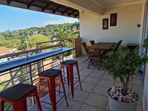 德班Africatamna Self Catering House的设有一个配有桌子和凳子并享有美景的阳台。