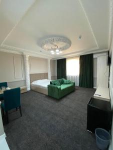 塔拉兹Sapphire hotels的一间卧室配有一张床和一张绿色沙发