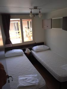 阿梅利亚Mobile home Comfort Ameglia - Camping River- 326- 6 pers的带窗户的客房内的两张床