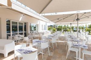 La Ville-aux-DamesWestotel Tours Val de Loire的一间设有白色桌子和白色椅子的餐厅