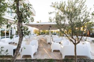 La Ville-aux-DamesWestotel Tours Val de Loire的餐厅设有白色的桌子和白色的椅子,树木繁茂