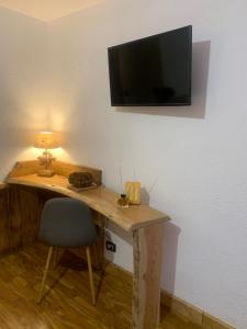 拉特乌伊莱Hotel Coeur Du Village的一张桌子、椅子和墙上的电视